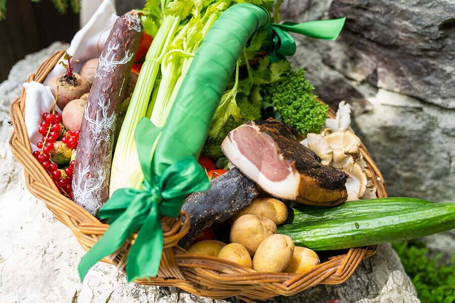 Korb mit frischen, regionalen Lebensmitteln und Wurstwaren, dekorativ mit Schleifen gebunden.