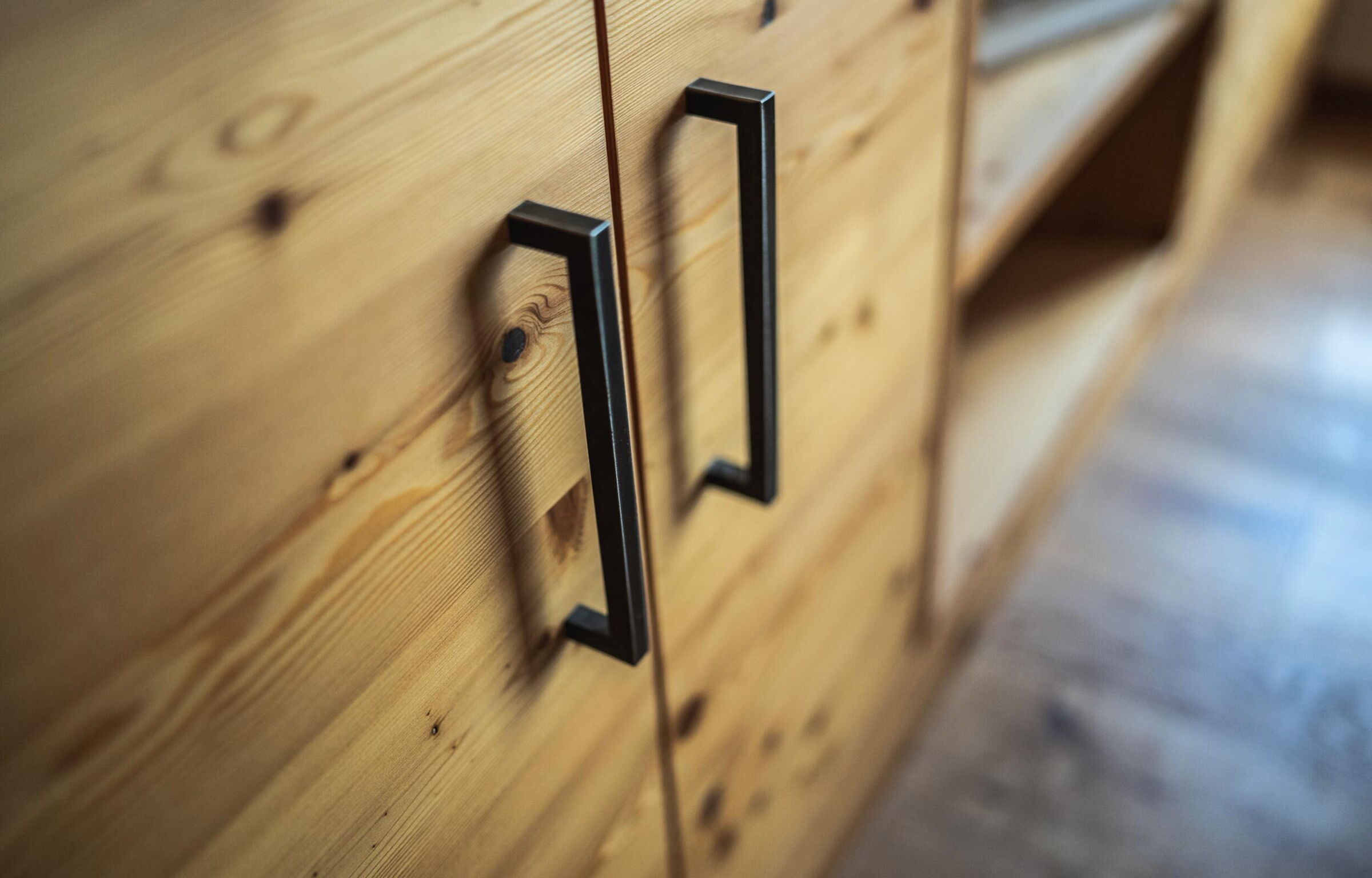 Nahaufnahme eines handgefertigten Holzschranks mit eleganten Metallgriffen im Chalet.