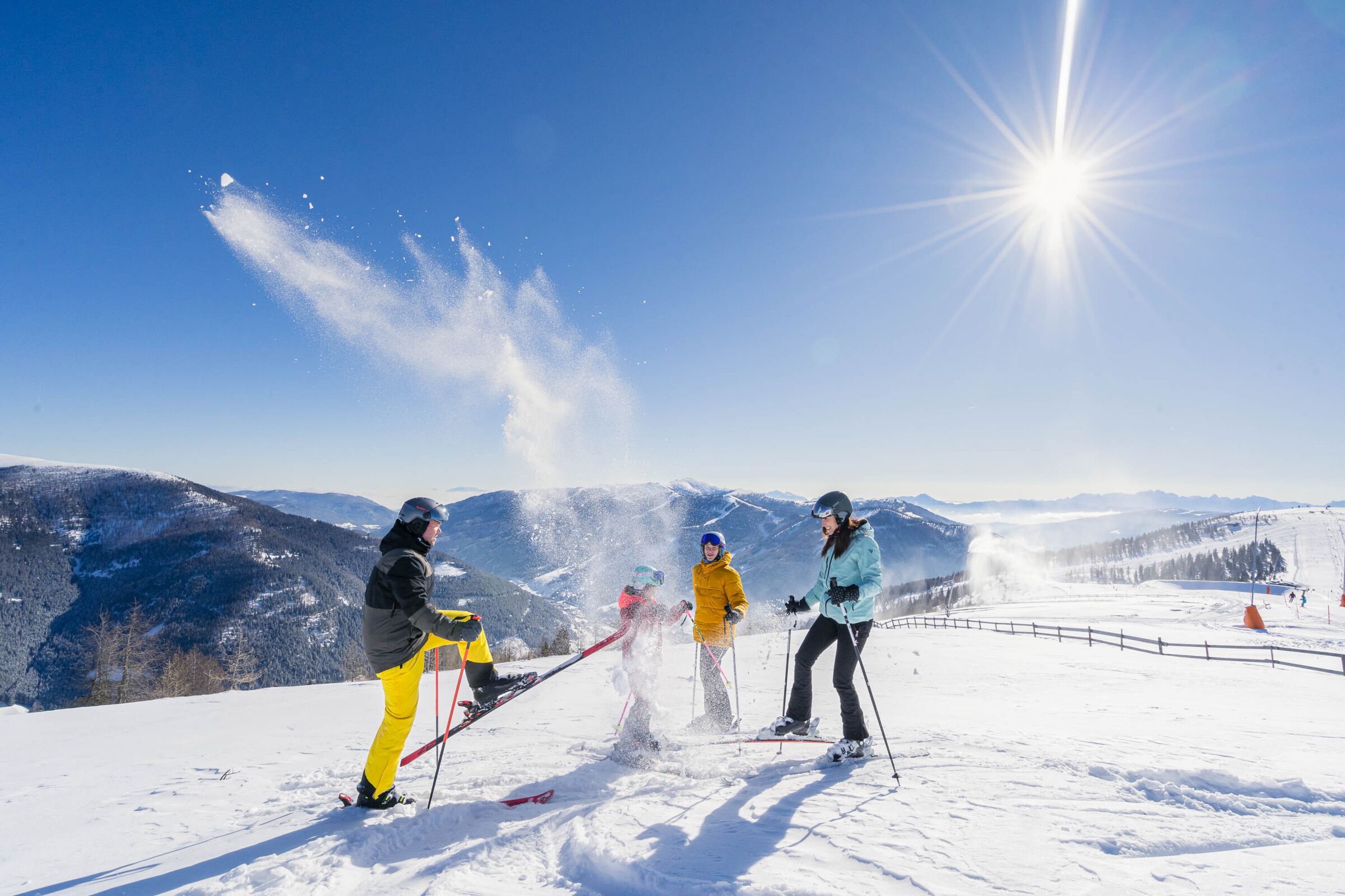Familie genießt sonniges Skifahren in den Bergen bei blauem Himmel und klarem Wetter.