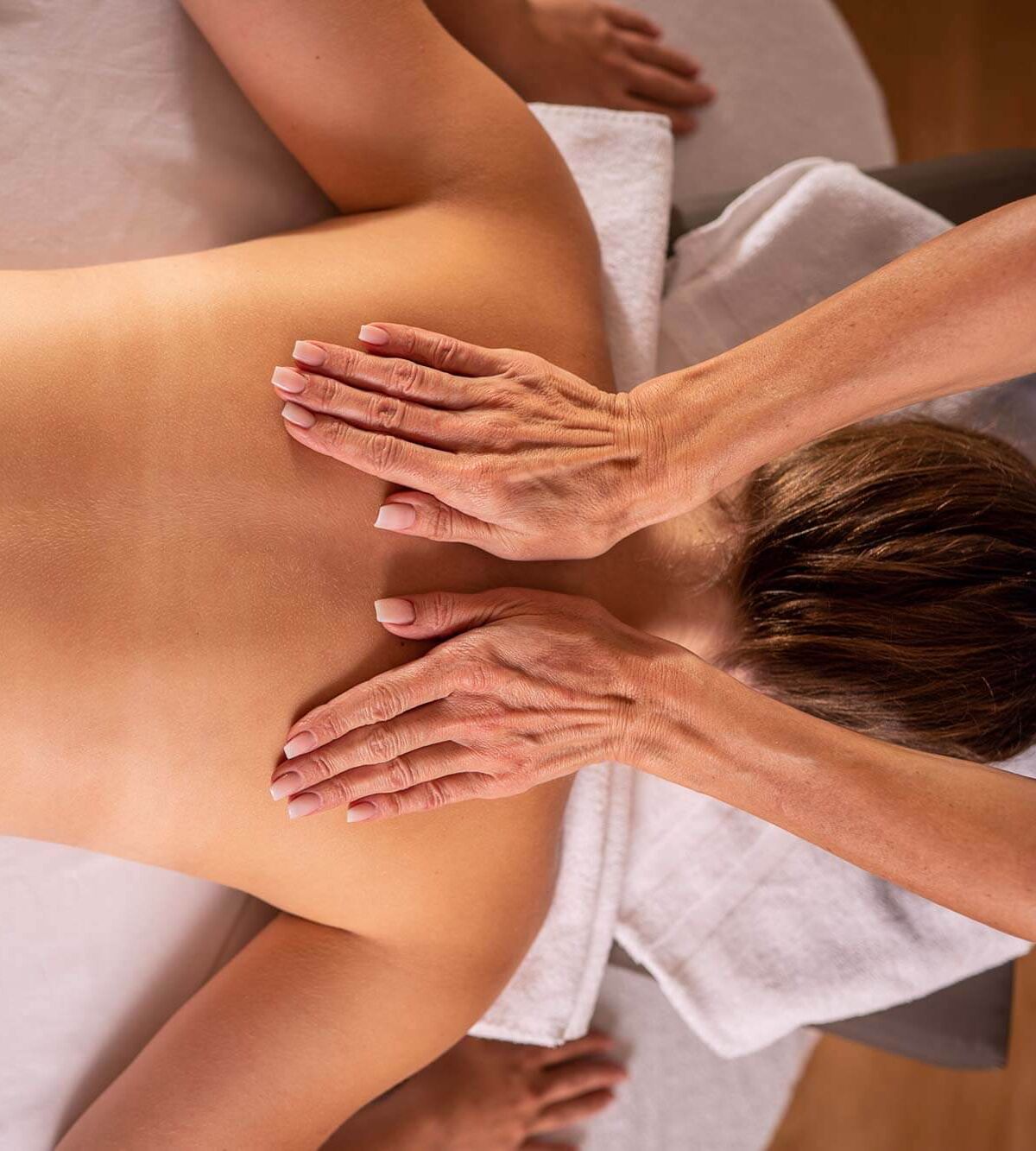 Frau erhält eine wohltuende Massage zur Entspannung auf einem weißen Handtuch.