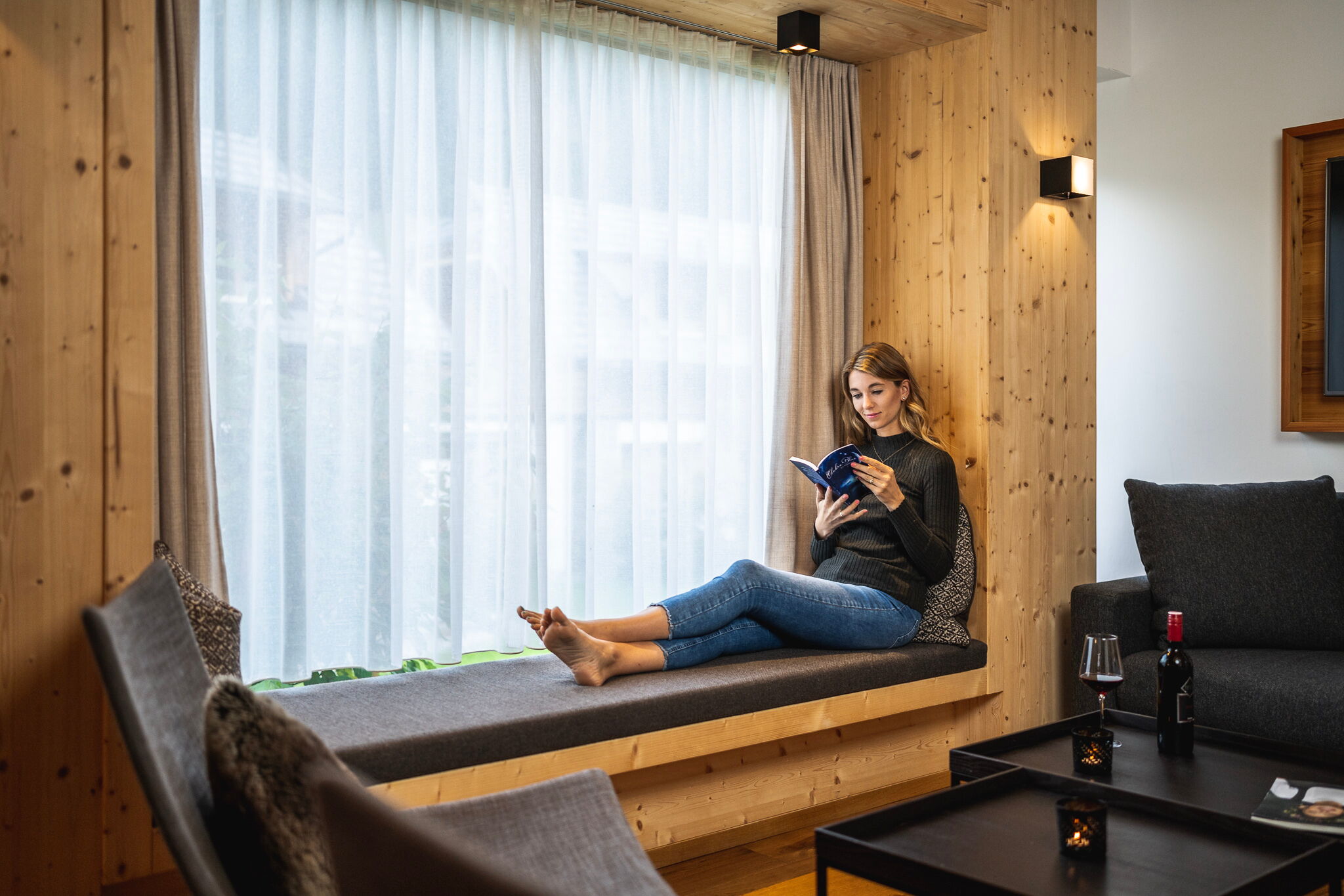 Woman relaxing with a book in a cozy, wood-paneled sitting area in the chalet.