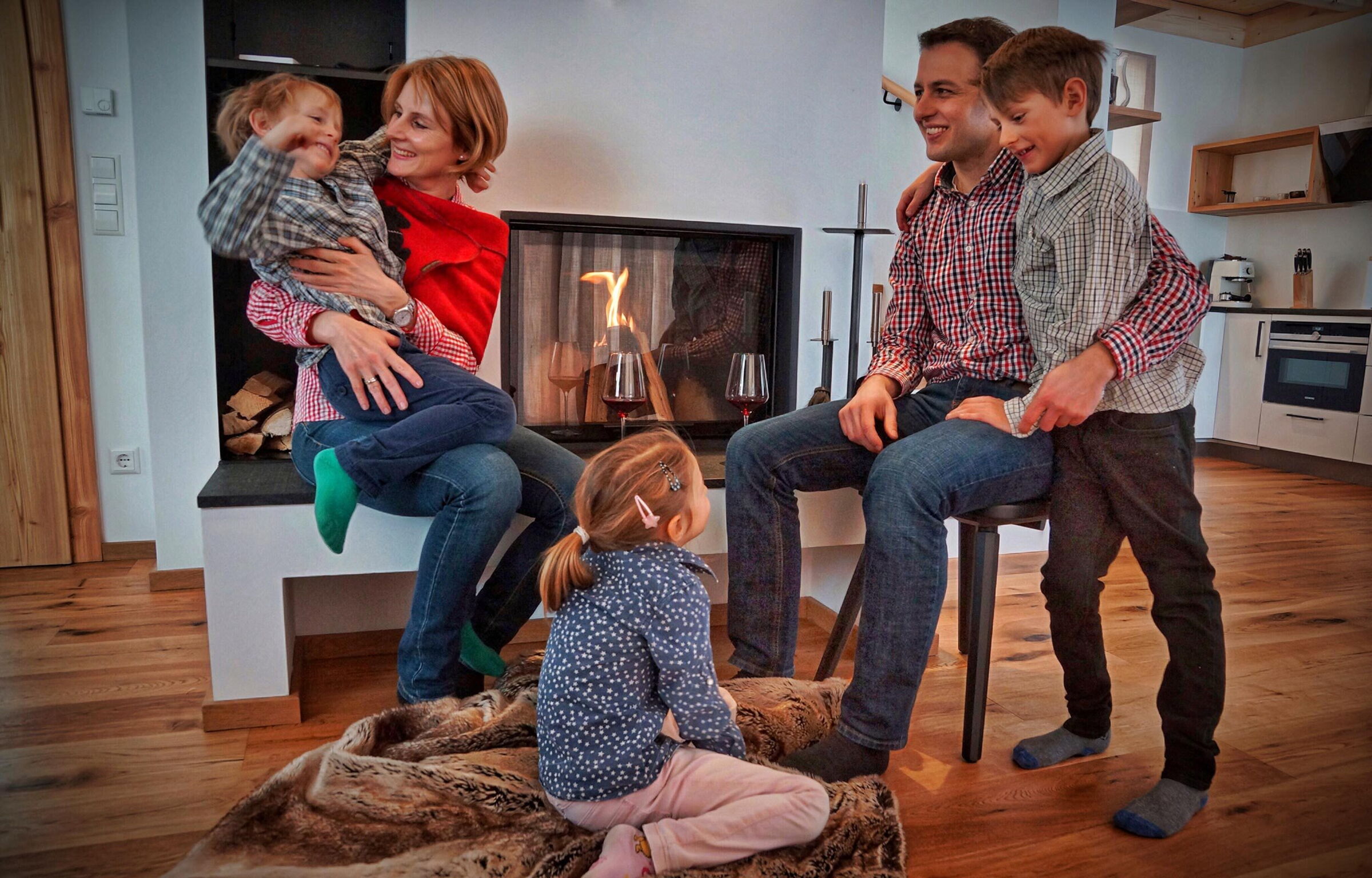 Familie genießt gemütliche Momente vor einem warmen Kamin in einem Chalet.