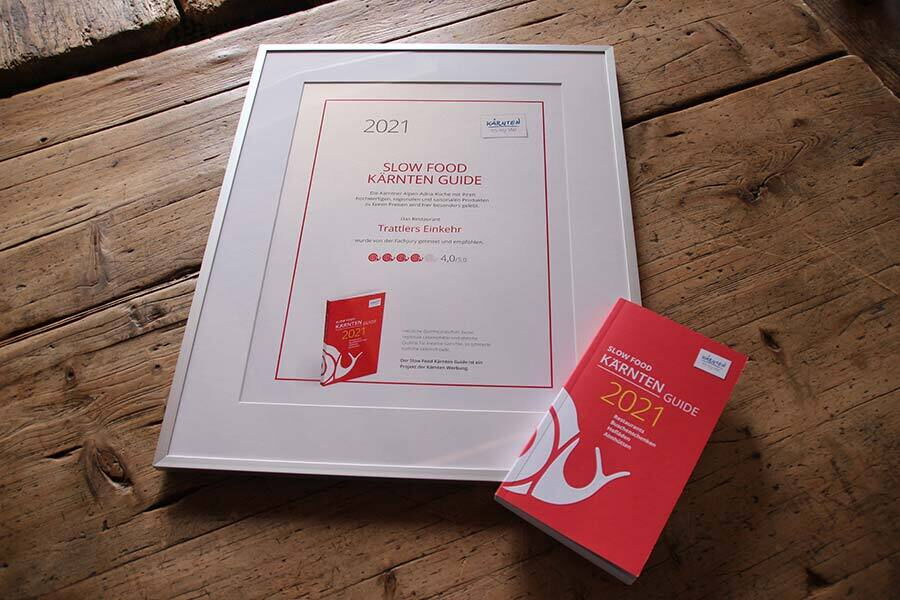 Certificate and book of the Slow Food Carinthia Guide on a wooden table.