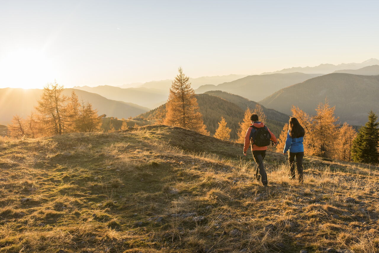 Zwei Wanderer genießen die Abendsonne in den goldenen Nockbergen.