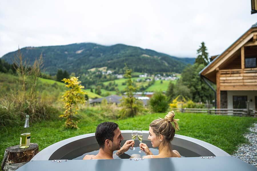 Couple enjoying a hot tub with champagne against an alpine backdrop in Carinthia.