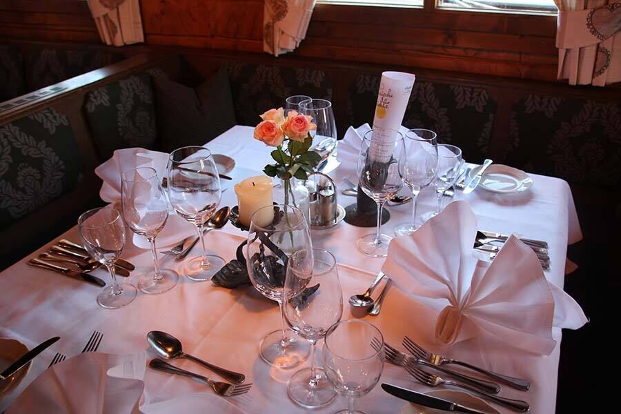 Finely laid table with fine glasses, cutlery and decorative flower arrangements.