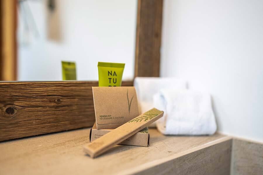 Naturprodukte in nachhaltiger Verpackung auf einem Holzregal im Badezimmer.