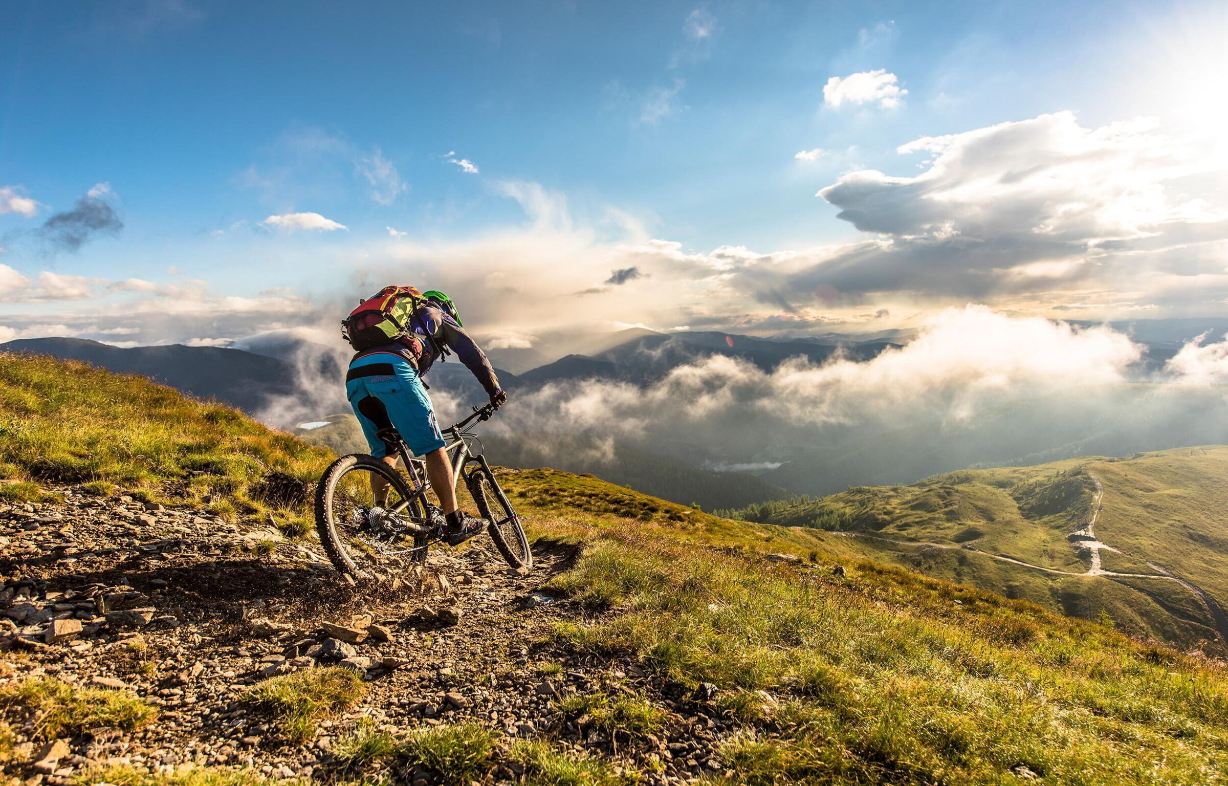 Radfahrer genießt Berglandschaft mit dramatischem Himmel und Wolken im Hintergrund.