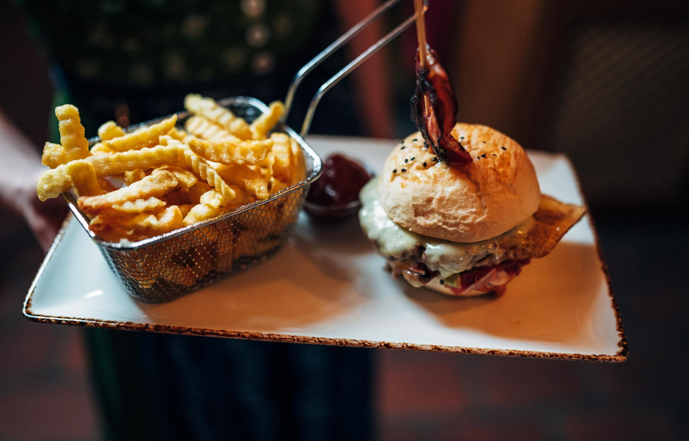 Burger und Pommes auf rustikalem Teller, appetitlich serviert im stimmungsvollen Ambiente