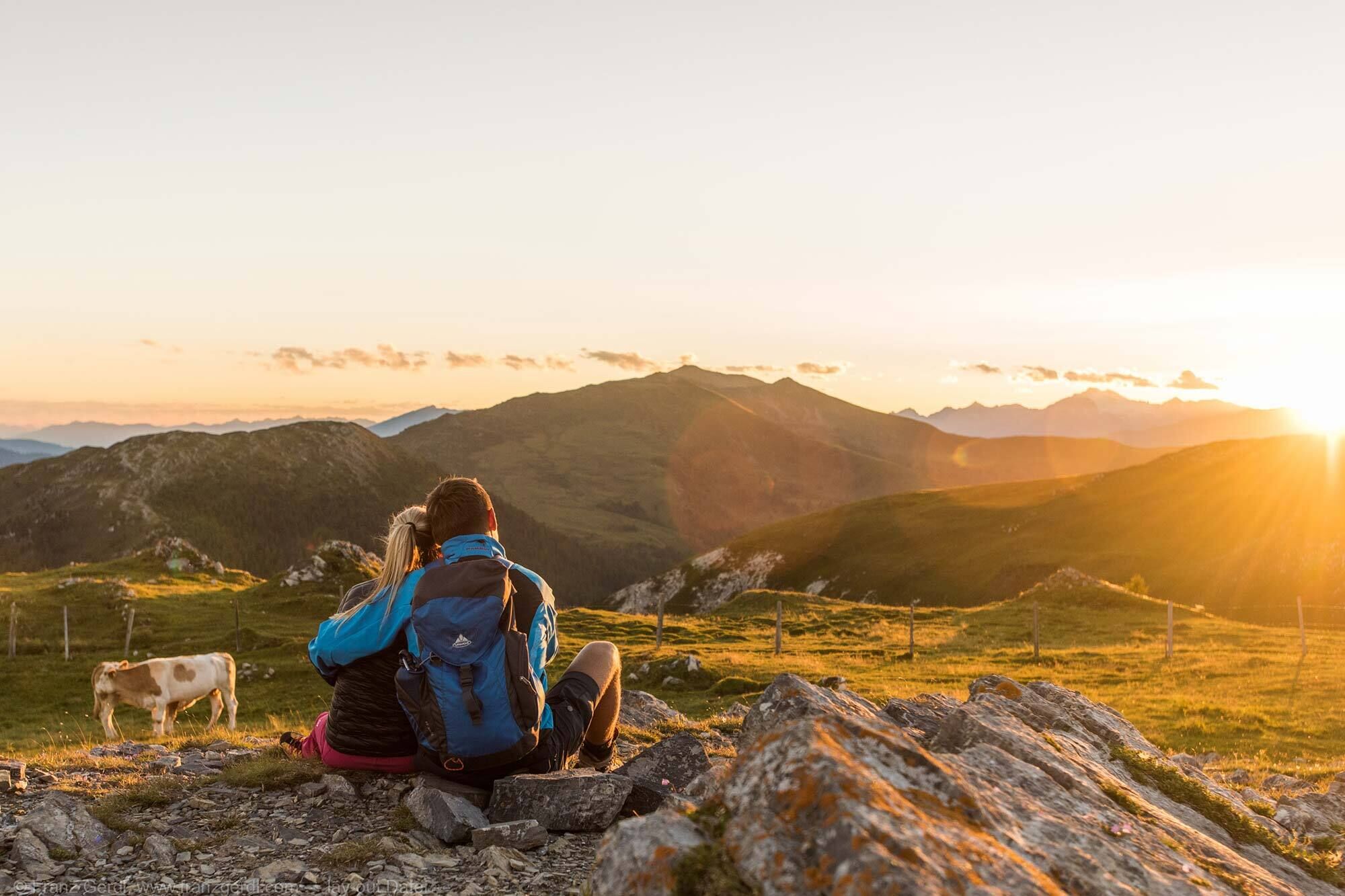 Couple enjoying the sunset with a panoramic view of the Alps in the Nock Mountains, Carinthia.