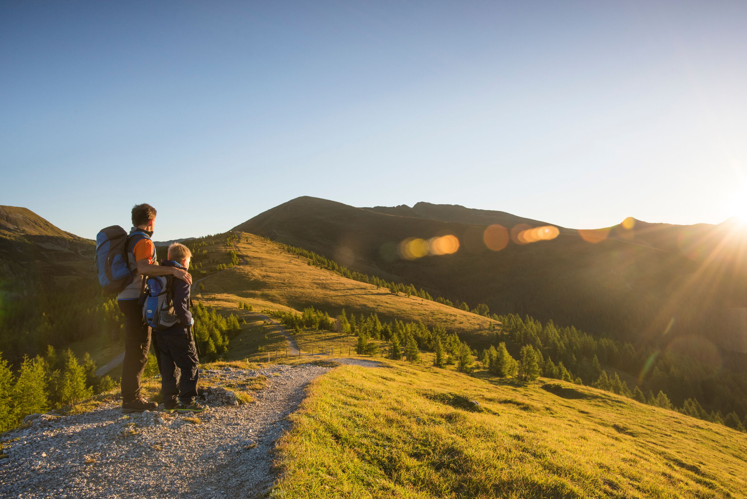 Vater und Sohn genießen Panorama in sonniger Berglandschaft bei Sonnenaufgang.