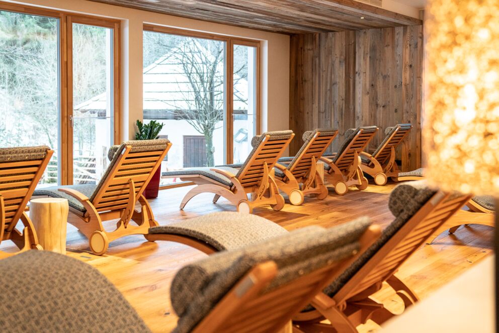 Cozy relaxation area with wooden loungers and large windows overlooking nature.
