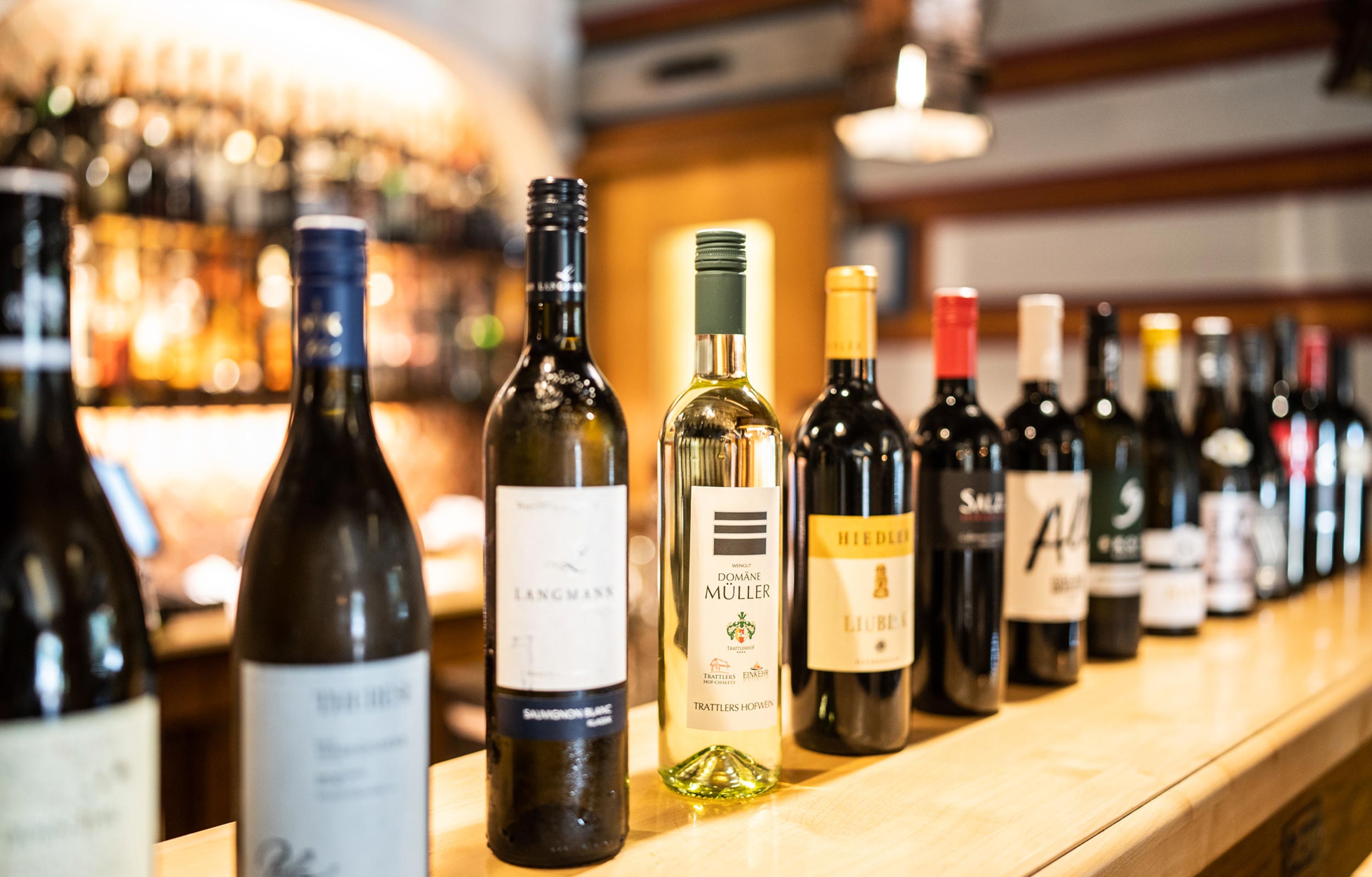 There are many different wines lined up on the bar.